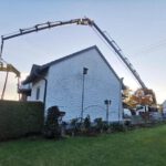 Effer 2055 Ladekran von Weiss Krandienstleistungen hebt eine Last präzise über ein Wohnhaus unter einer Stromleitung.